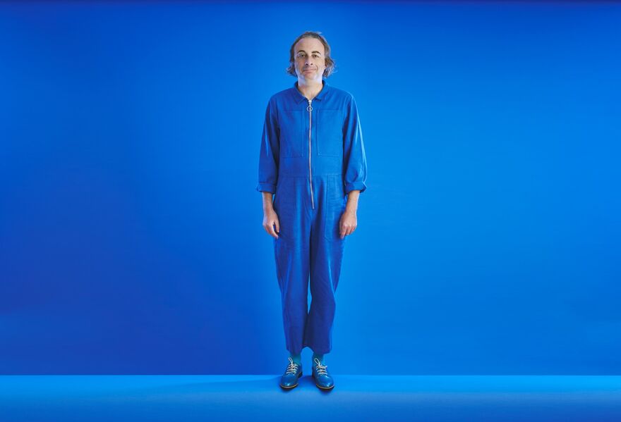 Paul Foot in a blue jumpsuit and blue shoes blending into a blue backgroun