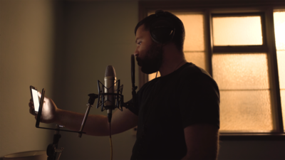 A young man raps into a microphone with lyrics on his mobile