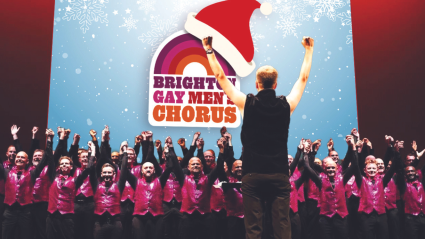 large group of men with a man leading them at the front all have their arms in the air and their with fists closed. Altogether they form a chorus