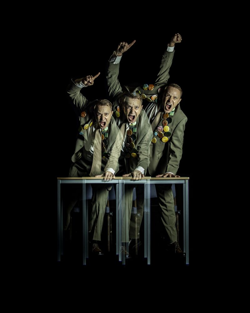 Three men leaning on a desk, looking angry and shouting, waving their right arm in the air with a fist or point