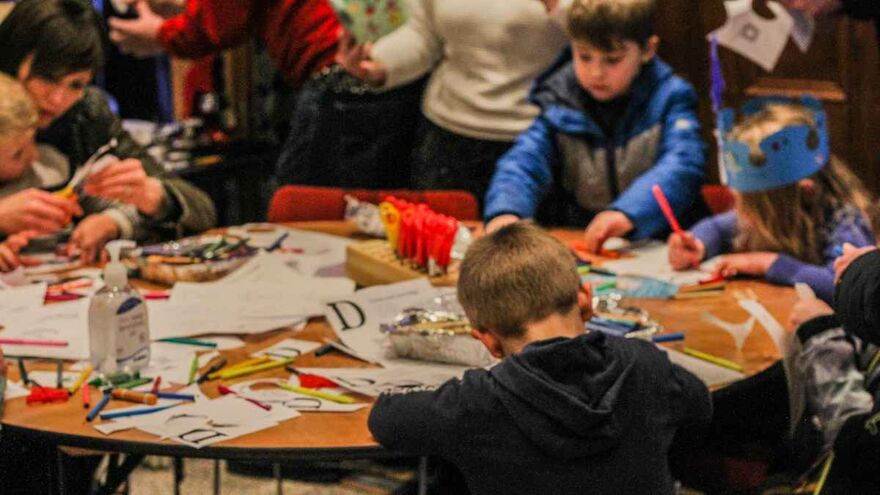 Craft workshop at Brighton Dome. Young children are sat crafting at a table covered with craft paper and equiment