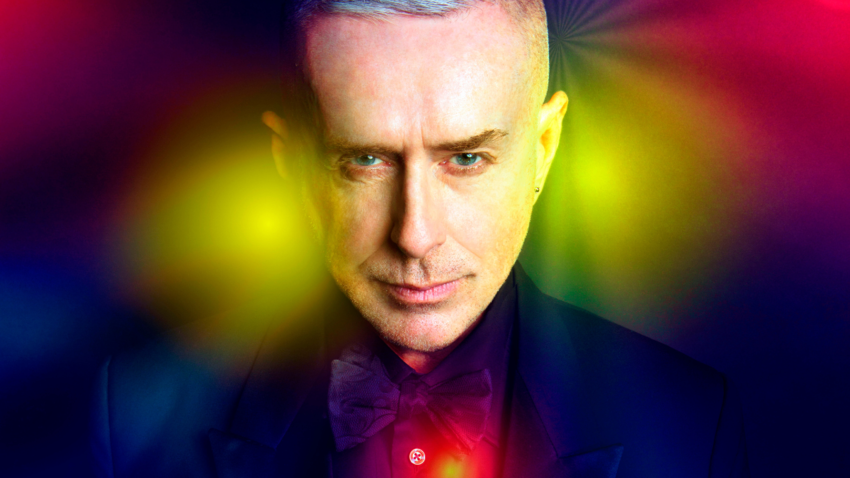 man with gray hair wearing formal attire: blazer, shirt and bow-tie looks directly at camera