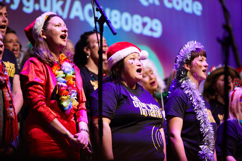 people stand together on a stage as they sing a choir song