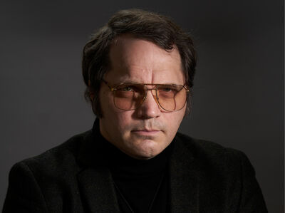 white male with aviator glasses stares into camera