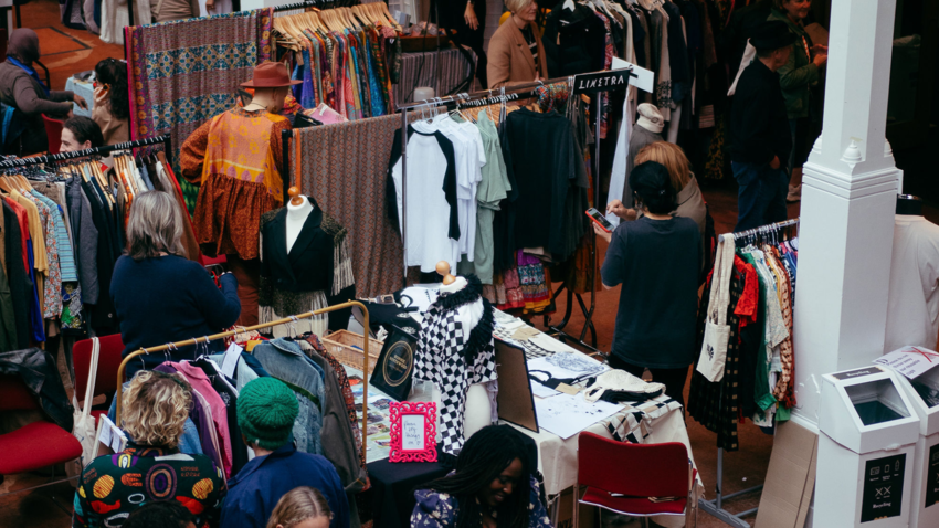 A photo of lots of clothing racks and people browsing clothes