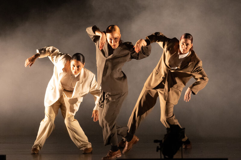 Three dancers on stage wearing oversized suits