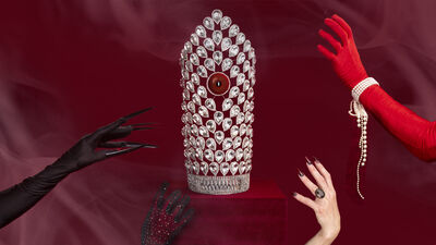 A diamond crown on a red velvet box. Four arms are reaching out towards the crown. Some are wearing gloves and jewelry
