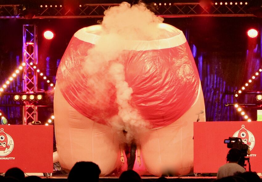A giant inflatable bottom on stage, surrounded by dry ice, with Stefan Gates emerging from underneath