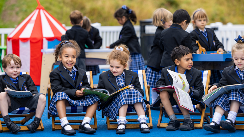 School children sitting on mini deckchairs in their school uniform