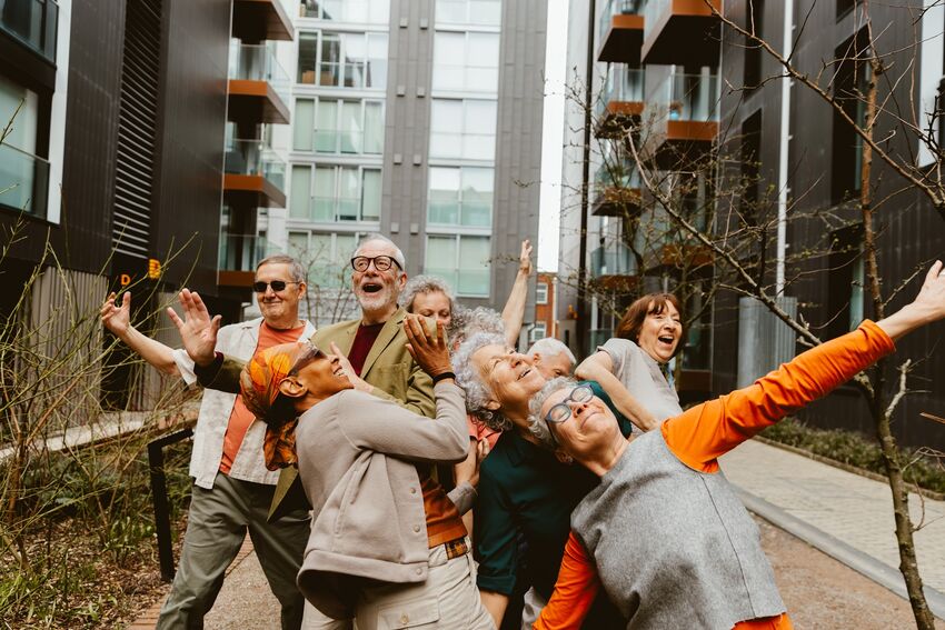 A group of older dancers smiling and moving outside The Dance Space