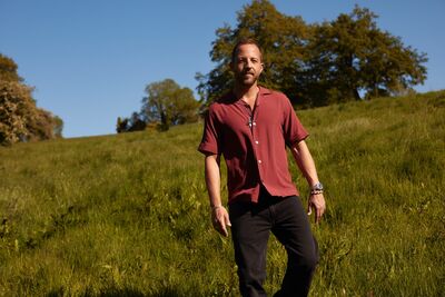 James Morrison walking in a field wearing a red short-sleeved shirt