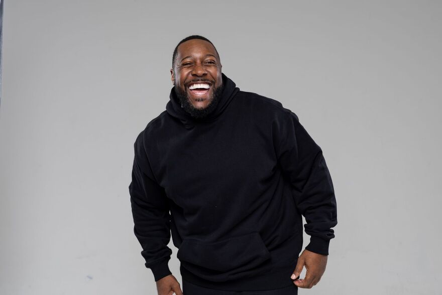 Aurie Styla wearing a black hoodie and laughing at the camera