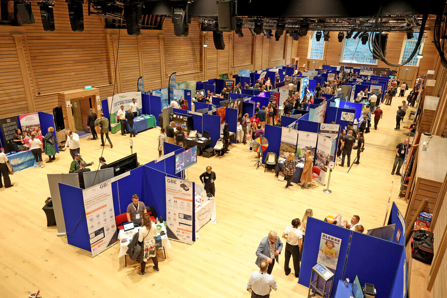 Lots of stalls and people at a business show in the corn exchange