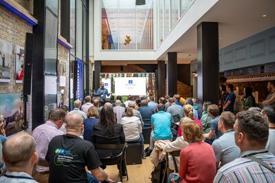 A man is doing a presentation in front of a seated audience in the gallery bar at Brighton Dome