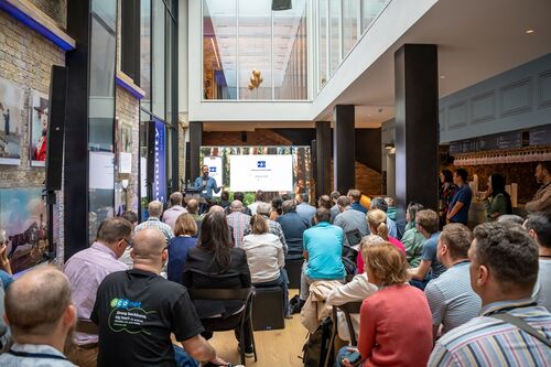 A man is doing a presentation in front of a seated audience in the gallery bar at Brighton Dome