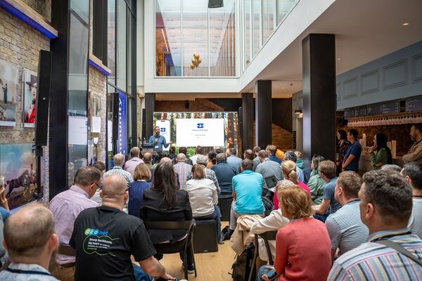 A man is doing a presentation in front of a seated audience in the gallery bar at Brighton Dome