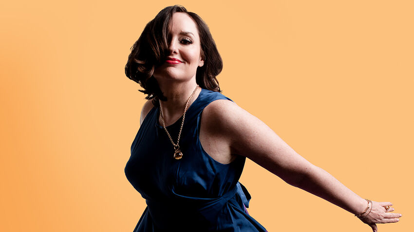 Deborah Frances-White poses in a blue dress