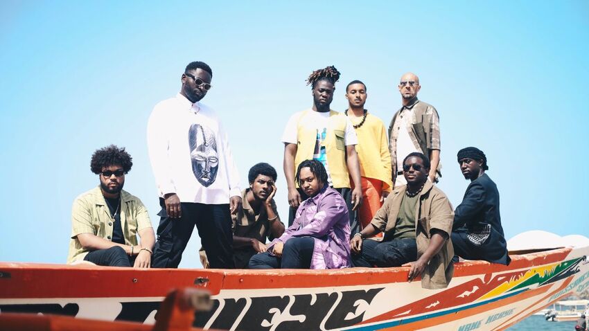 The 9 members of Balimaya Project sat and stood in a boat