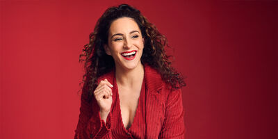 Janine Harouni in a red blazer over a red background