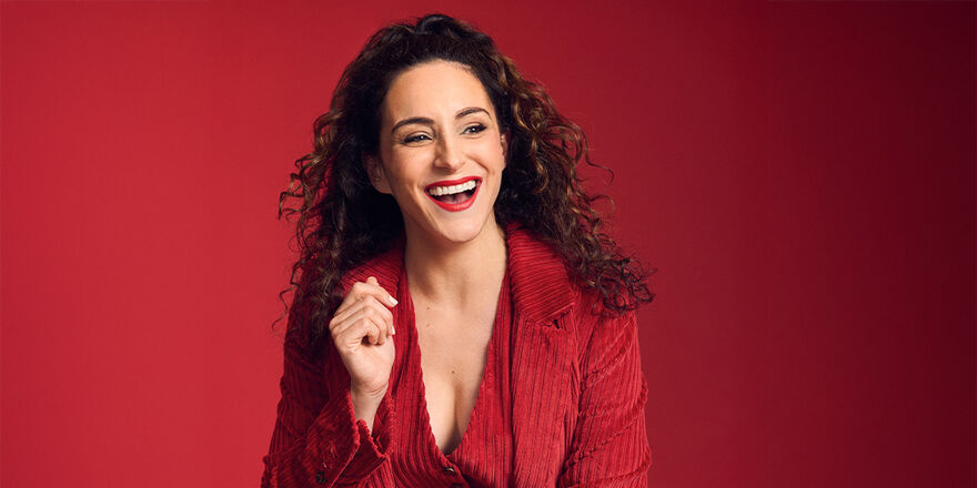 Janine Harouni in a red blazer over a red background